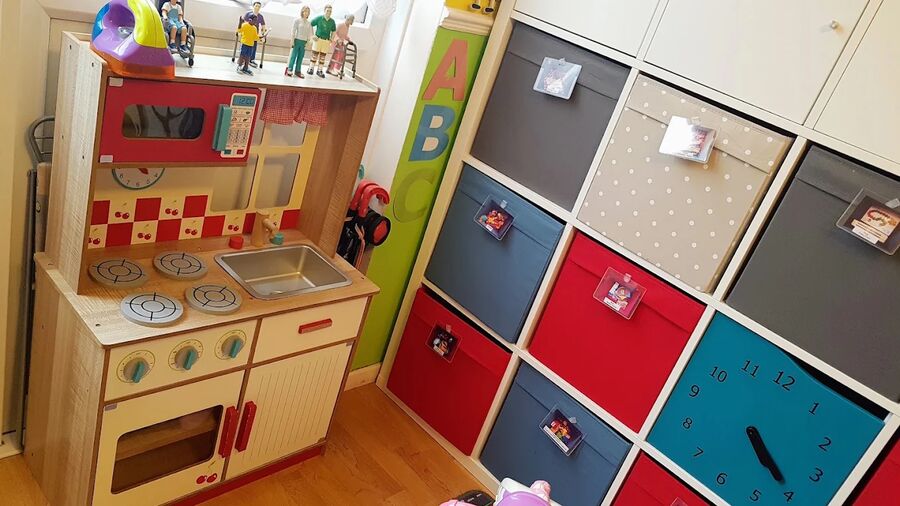 A wooden play kitchen next to the storage cubes.