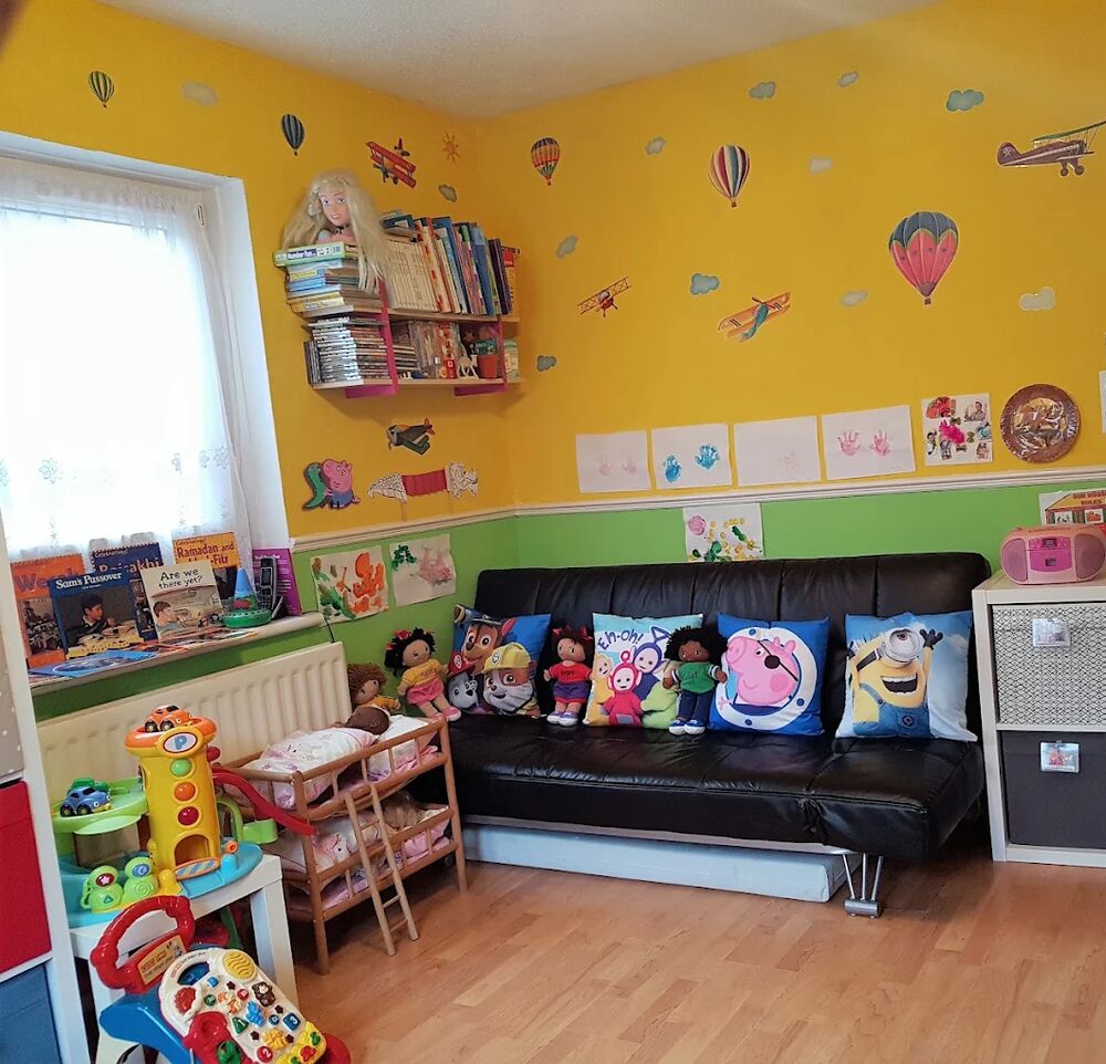 The playroom from the other side, with the sofa, wall pictures and shelves of toys.