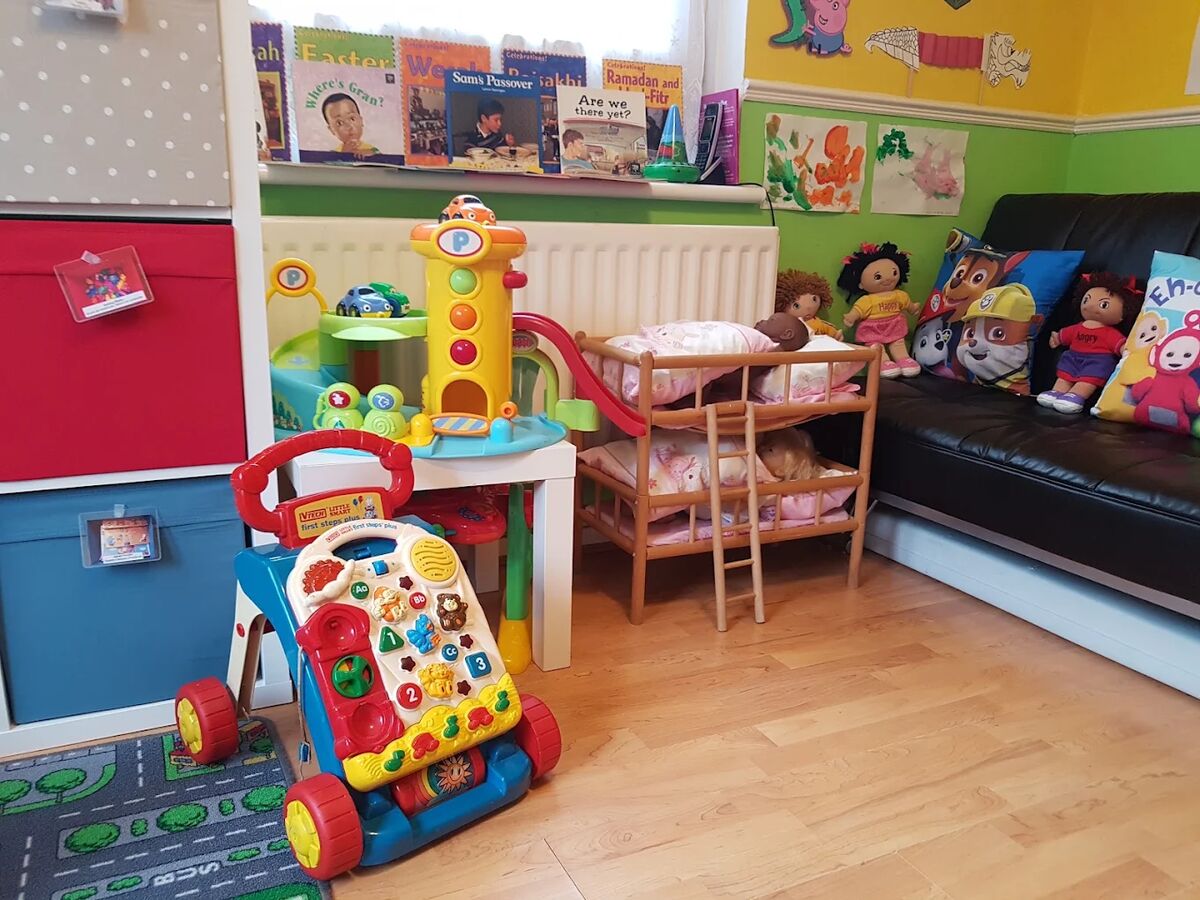A sofa with character cushions beside shelves of books and toys.