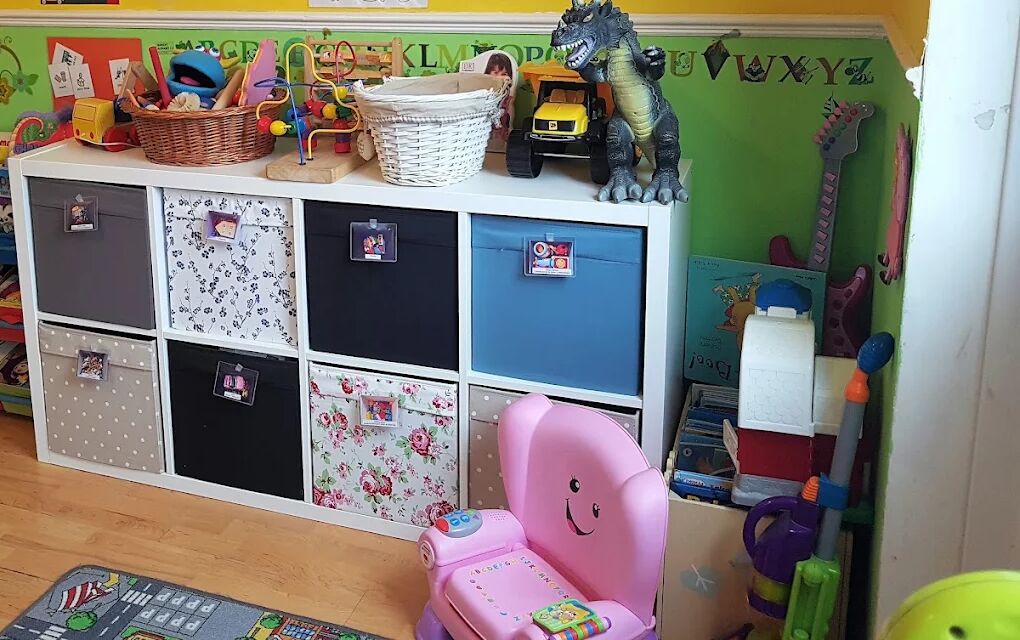 Toy storage cubes and a rack of picture books against a green and yellow wall.
